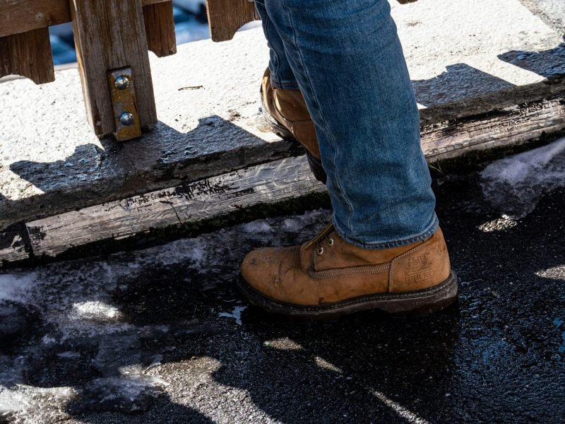 person in blue denim jeans and brown leather boots